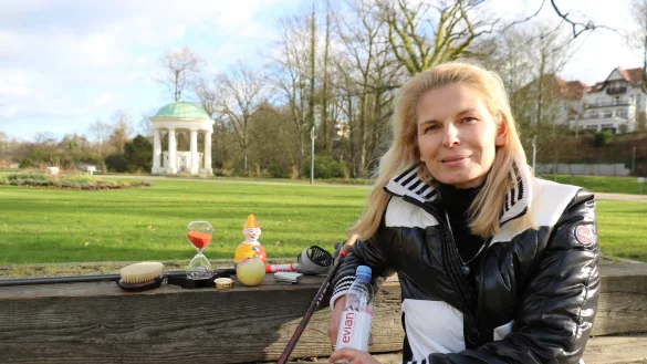Iris &Uuml;ckermann sitzt im Kurpark. Sie hat einige ihrer Utensilien mitgebracht, die sie bei ihrem Kneipp-Coaching einsetzt, um das Ganze besser zu veranschaulichen: Darunter eine Sanduhr, ein Stehauf-M&auml;nnchen und Wasser. - &copy; Alexandra Schaller