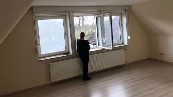 Iris Lange steht in ihrer ausgeräumten Wohnung und blickt nach draußen. Rechts sieht man das Dach des Gebäudes, in dem ihr Ex-Vermieter wohnt. Foto: Sven Kienscherf - © Sven Kienscherf