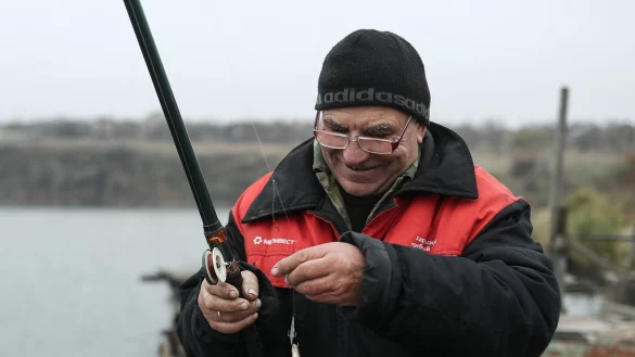 Ein Angler hat einen kleinen Fisch gefangen. - © picture alliance/dpa