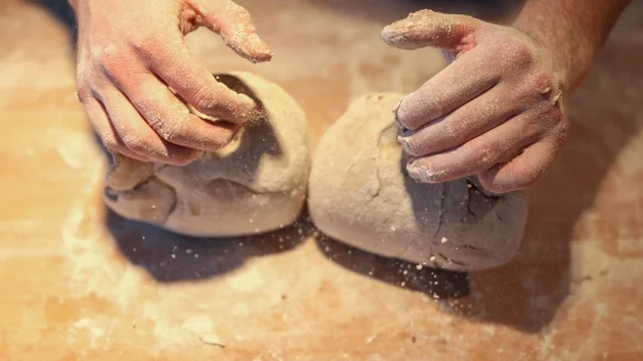 Traditionsreiches Handwerk: Ein B&auml;cker formt mit seinen H&auml;nden zwei Brote. Die Corona-Krise betrifft auch diese Branche. - &copy; dpa