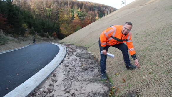 Tobias Fischer vom Landesbetrieb Stra&szlig;en.NRW zupft am Sisal-Netz, das bis fast zur Kuppe des H&uuml;gels reicht. Es stabilisiert die abgeflachte B&ouml;schung und sch&uuml;tzt die sprie&szlig;enden Gr&auml;ser. - &copy; Dieter Asbrock