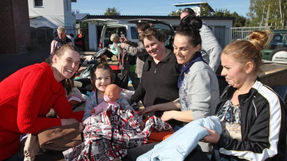 Passt etwas l&auml;nger: In die Jacke m&uuml;sste die kleine Amina erst noch reinwachsen, meint Sylvia Kretzschmar von der Kleiderkammer der Kirchengemeinde (links). Amina, ihre Mutter Ardito Homjo (zweite von rechts), und Naze Vogli (rechts) sind aus Albanien geflohen und machen mit vielen Helfern, darunter Christina Kaufeld (dritte von rechts), beim Sortieren der Kleiderspenden mit. - &copy; Bernhard Preu&szlig;