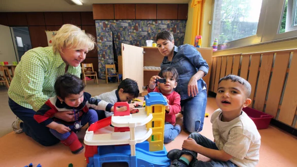 Die Fl&uuml;chtlingskinder Nawasa, Masih, Muoyad und Nuras spielen mit Erzieherin Natalia Scherer und Claudia Haustein eine Runde mit dem Parkhaus. - &copy; Bernhard Preuss