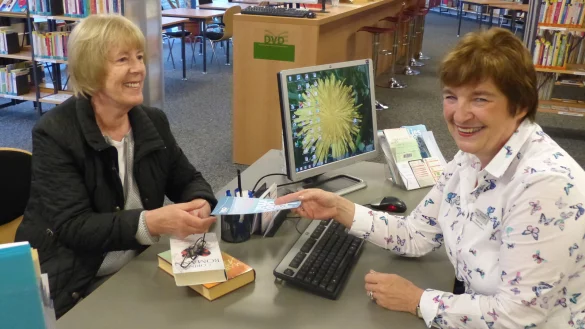Büchereikundin Margitta Schilp (links) erhält einen Flyer zu den neuen Öffnungszeiten von Regine Link. - © Laureen Hannig