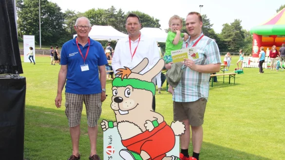Maskottchen &bdquo;Hermi" wirbt f&uuml;r Sport im Verein: (von links) Karl-Heinz Danger, Frank Hilker und Michael Peuker mit Sohn Jonathan pr&auml;sentieren den &bdquo;Sports4kids"-Gutschein. - &copy; Lorraine Brinkmann