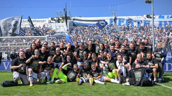 Spieler, Trainer und Mitarbeiter von Arminia Bielefeld genießen die ausgelassenen Aufstiegsfeierlichkeiten im Sportpark Unterhaching vor den mitgereisten Fans. - © Teresa Kroeger/RHR-FOTO