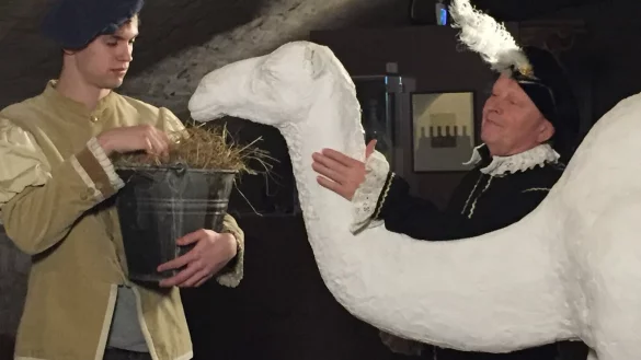 Das lebensgroße Dromedar aus Gips ist im Weserrenaissance-Museum zu finden. Hier ist es mit Komparsen, die Graf Simon VI. und einen Tierpfleger darstellen, in Szene gesetzt. - © Weserrenaissance-Museum Schloss Brake