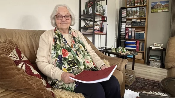 Adelgunde Sander sitzt in ihrem Wohnzimmer in La&szlig;bruch, auf dem Scho&szlig; die rote Kladde mit Erinnerungen, die ihre Mutter vor 30 Jahren niederschrieb. - &copy; Bildrechte: Adelgunde Seidel