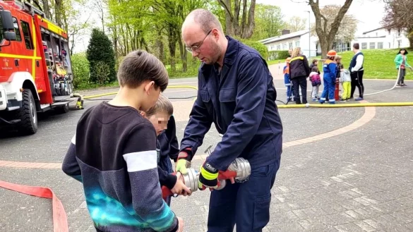 Der Leiter der Jugendfeuerwehr H&ouml;rste, Jan-Lukas Schlink, zeigt den Kindern bei einem Spielnachmittag am Kinderheim, wie man Schl&auml;uche miteinander verbindet. - &copy; Astrid Sewing