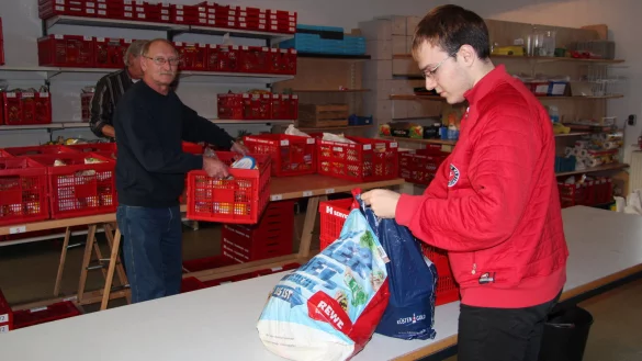 Kein Gedrängel bei der Kisten-Ausgabe: Der junge Mann – ein syrischer Flüchtling – kann in Ruhe seine Lebensmittel einpacken. Jürgen Schröder aus Lothe, einer der rund 70 ehrenamtlichen Helfer, reicht ihm die Kiste, deren Inhalt er in seine Tüten umpackt. Was er nicht möchte, lässt er zurück. - © Buhrmester
