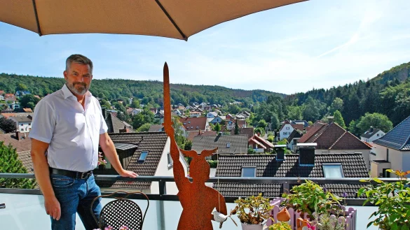 Dirk Becker im Sommer auf der Balkonterrasse seines Hauses. Neben ihm steht eine Hermann-Skulptur, der Blick geht &uuml;ber Oerlinghausens H&auml;user bis zu den Ausl&auml;ufern des Teutoburger Waldes. - &copy; Archivfoto: Gunter Held