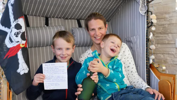 Janik (8) und Mattis (5) sitzen mit ihrer Mutter Claudia Fleer im eigenen Strandkorb. Sie haben einen Brief vom Finder der Flaschenpost bekommen - und eine Piratenfahne. - &copy; Peter Unger