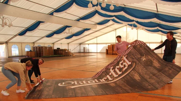Beim Aufbau: Die Organisatoren (von links) Anna Kleinemas, Frank Weingarten, Peter Daletzski und Johannes Strake rollen im Festzelt ein Oktoberfest-Banner aus. - &copy; Jana Beckmann(LZ)