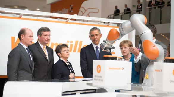 Bundeskanzlerin Angela Merkel (2.v.r, CDU) und US-Präsident Barack Obama (M) besuchen den Stand von Weidmüller auf der Hannover Messe und betrachten einen Roboter von Kuka. Die USA sind dieses Jahr das Partnerland der Messe. - © dpa
