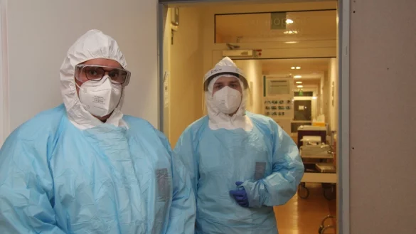 Nur in voller Montur k&ouml;nnen Julian Mendaszweski (links) und Robin Schneckener die Isolierstation betreten. Sie selbst laufen vermutlich nicht Gefahr, sich anzustecken: Sie haben beide bereits eine Corona-Erkrankung hinter sich. Die Rose-Klinik hat aus Leichtbauw&auml;nden eigens eine Schleuse vor die eigentliche Eingangst&uuml;r der Station gebaut. - &copy; Marianne Schwarzer