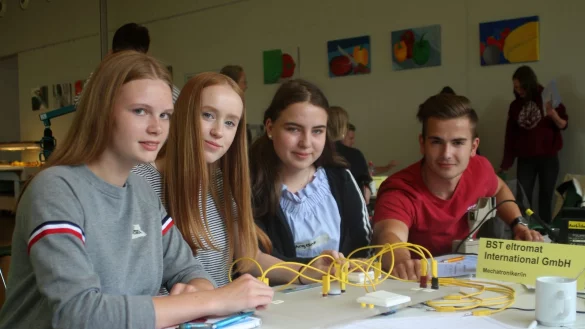 Tüfteln: (von links) Sarah, Vanessa und Angelique versuchen beim Berufsparcours in der Gesamtschule herauszufinden, mit welcher elektrischen Schaltung sie die Lampe zum Leuchten bringen können. Marvin Bischoff von der Firma BST Eltromat gibt Tipps. - © Thomas Dohna