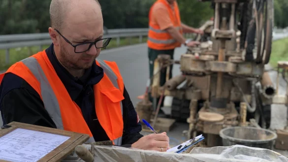 Projektgeologe Niko Miera macht eine erste Sichtungsprobe des Gesteins, auf dem die neue B 66 zwischen Barntrup und Gro&szlig;enmarpe einst verlaufen soll. Im Hintergrund holt der Kollege mit dem Bohrger&auml;t Meter um Meter aus dem Untergrund hervor. - &copy; Till Brand