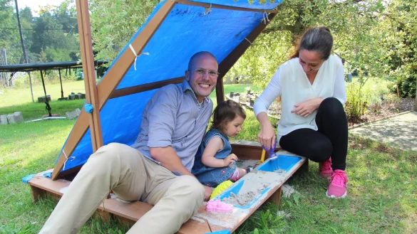 Martin Thiel und seine Frau Manuela Thiel spielen gemeinsam mit T&ouml;chterchen Romy-Franziska im Sandkasten im Garten. Auch das Trampolin im Hintergrund wird ab und an genutzt. - &copy; Nadine Uphoff
