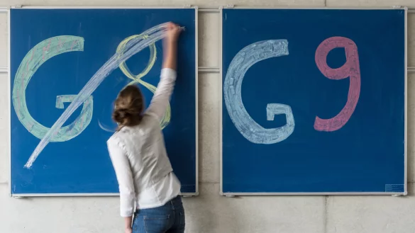 Illustration: Eine Schülerin der Oberstufe streicht an einem Gymnasium «G8» an einer Tafel durch, daneben lässt sie «G9» unberührt. - © dpa