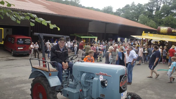 Bernhard Fasse aus Asendorf ist stolz auf seinen Trecker-Oldtimer von 1957. Er und viele weitere Aktive, Vereine und Direktvermarkter (im Hintergrund) freuen sich &uuml;ber den Andrang beim &bdquo;Schwoof auf dem Hof". - &copy; Werner Hoppe