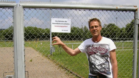 Vorsitzender Christian Pischczan steht vor dem verschlossenen Tor mit dem Warnschild am Sportplatz der SG Kalldorf. Scherben machen den Platz unbespielbar. - &copy; Wulf Daneyko