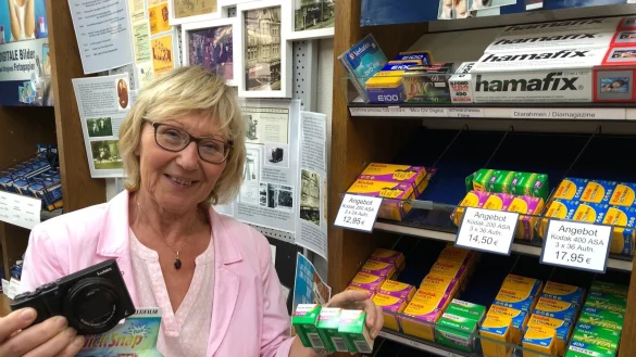 Fotogesch&auml;ft im Wandel: Laut Ingrid Mildner-Biesemeier wird es immer schwieriger, analoge Filme zu bekommen, wie sie sie in der Hand h&auml;lt und von denen sich weitere im Regal hinter ihr befinden. "Schuld" daran ist die rasante Entwicklung der digitalen Fotografie. Ein aktuelles Panasonic-Modell h&auml;lt sie in der anderen Hand - neben einer analogen Einwegkamera, die ebenfalls aktuell in Mode ist. - &copy; Thomas Reineke