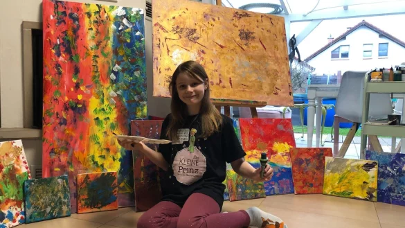 Emmi Lou (10) pr&auml;sentiert stolz ihre Bilder, die ab Freitag in Lemgo ausgestellt werden. Die gro&szlig;e Leinwand auf der Staffelei hei&szlig;t "Goldrauschen", das Bild links daneben "Bunter Hagel". Sie malt mit Acrylfarben. - &copy; Karolina Schmidt