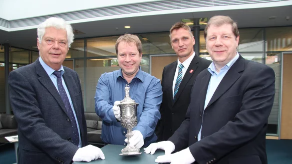 Empfindliches Schmuckst&uuml;ck: Nur mit Handschuhen darf der Silberpokal angefasst haben, den B&uuml;rgermeister Dr. Wolfgang Honsdorf, Stadtarchivar Arno Beuke, Sparkassen-Regionalleiter Marko K&ouml;nig und Dr. Stefan Wiesekopsieker vom Heimat- und Versch&ouml;nerungsverein hier in der Schalterhalle der Sparkasse Sch&ouml;tmar pr&auml;sentieren. - &copy; Dieter Asbrock