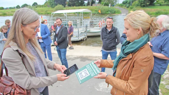 Die Weserf&auml;hre wird viel genutzt. Sensoren &uuml;bermitteln neuerdings, ob die F&auml;hre einsatzbereit ist. Radler und Wanderer k&ouml;nnen die Daten im Internet &uuml;ber www.kalletal.de/weserfaehre abrufen. Das geht auch per QR-Code, wie Michaela Lehnert vom Kommunalen Rechenzentrum (links) und Corinna Will von der Gemeinde Kalletal demonstrieren. Die Schilder werden an mehreren Stellen aufgestellt. - &copy; Jens Rademacher