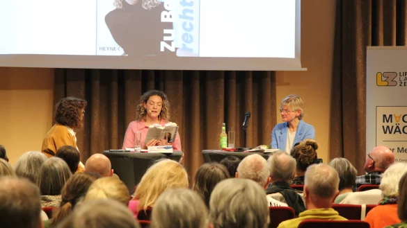 Sally Lisa Starken (Mitte) liest aus ihrem Buch. Auch die Moderatorinnen des Abends, Silke Buhrmester (links) und Claudia Biehahn, hören interessiert zu. - © Carolin Brokmann-Förster