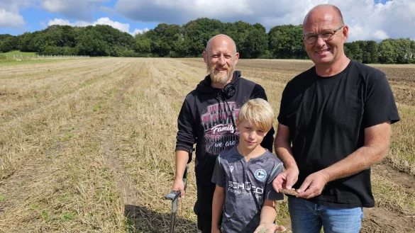 Benjamin Schulz (links) nimmt seinen Sohn Thore Zier gerne zum Sondieren mit. Die M&uuml;nzen, die Thore in der Hand h&auml;lt, sind historisch interessant, aber nicht wertvoll. Gleiches gilt f&uuml;r das Taschenmesser, das Alexander Horn in der Hand h&auml;lt: Er vermutet stark, dass es seinem verstorbenen Onkel geh&ouml;rte, der vor Jahrzehnten auf dem Acker gearbeitet hatte. - &copy; Astrid Sewing