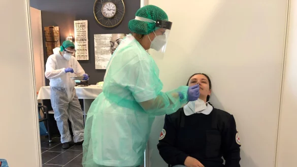 DRK-Mitarbeiterin Lisa Schachler (rechts) l&auml;sst sich f&uuml;r das Foto im Bad Salzufler Messezentrum von Simone Eschenbach testen. Im Hintergrund wertet Ugur Dervisoglu die Testergebnisse aus. - &copy; Sven Kienscherf