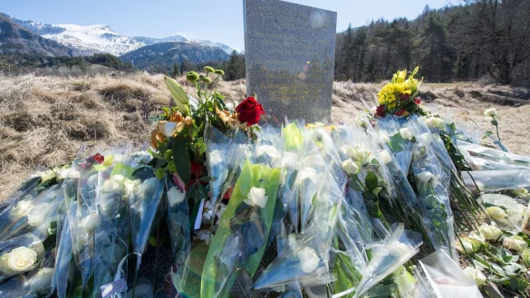 Inmitten von Blumen steht eine steinerne Gedenkstele mit der Aufschrift "In Erinnerung an die Opfer des Flugzeugunglücks vom 24. März 2015". Der Tag des Absturzes des Germanwings-Flug 9525 jährt sich zum zehnten Mal. - © Peter Kneffel/picture alliance/dpa