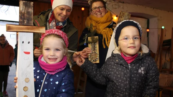 Auf dem Weihnachtsmarkt in H&ouml;rste haben Yara und Greta (vorne von links) unter der Anleitung von Anke Martin (hinten links) und Carola Stricker Schneemann-Stecker aus Holz gebastelt. - &copy; Sandra Castrup