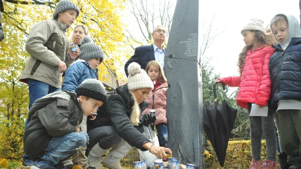 Nachfahren von Karla Raveh, darunter auch Enkel und bereits Urenkel, legen am Denkmal für Lemgos Ehrenbürgerin am Wall Steine nieder und zünden Kerzen an. - © Nicole Ellerbrake