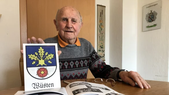 Heimatverbunden: Albert Siegert in seiner K&uuml;che mit den von ihm zusammengetragenen Aufzeichnungen und dem W&uuml;stener Wappen.&nbsp; - &copy; Sven Kienscherf