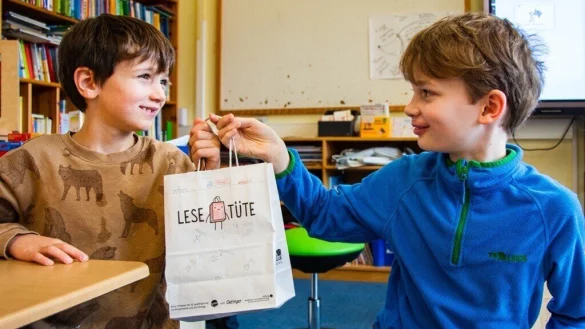 Erstklässler Michel (6, links) bekommt von seinem Lesepaten Maxi (10) aus der 4c eine selbst bemalte Lesetüte überreicht. - © Raphael Bartling