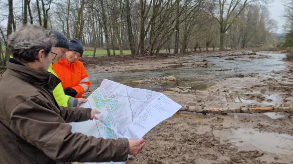 Jürgen Benning von der Unteren Wasserbehörde (von links), Klaus Leifels vom Planungsbüro UIH und Barbara von der Lippe von der Unteren Naturschutzbehörde schauen sich am Fluss noch einmal den Plan zur Renaturierung der Bega zwischen Bega und Barntrup an. - © Nadine Uphoff