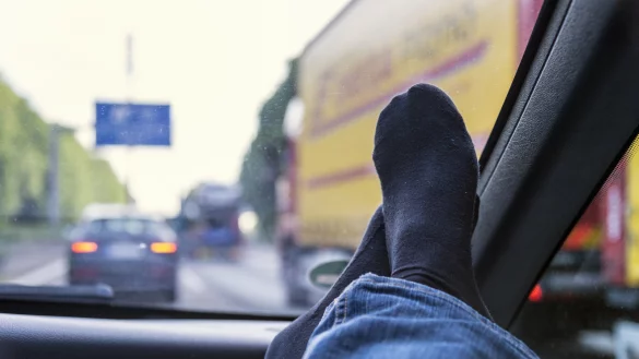 Auf der Autobahn: Die F&uuml;&szlig;e des Beifahrers liegen auf dem Armaturenbrett. - &copy; picture alliance