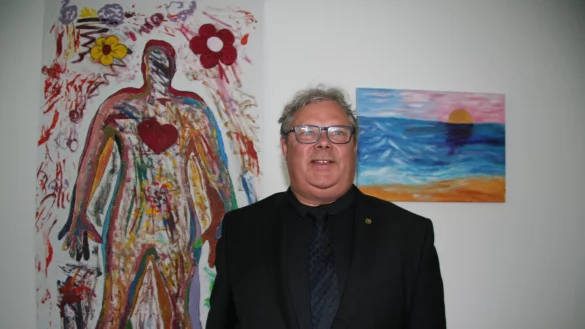 Pfarrer Christian Fischer, Mitinitiator des Projektes, vor Bildern, die Soldaten gemalt haben. - &copy; Cordula Gr&ouml;ne