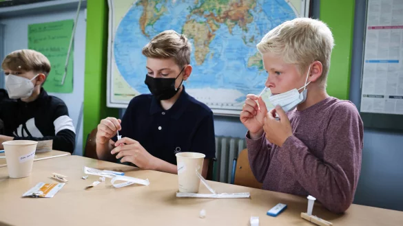 Drei Schüler testen sich unter der Aufsicht ihrer Lehrerin auf das Coronavirus. In weiterführenden Schulen in NRW testen sich Schüler und Mitarbeiter drei Mal pro Woche. - © picture alliance
