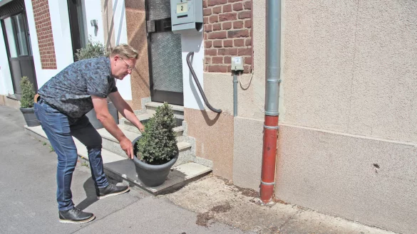Takis Poursanidis stellt seinen Blumenk&uuml;bel wieder richtig hin, nachdem dieser offenbar umgesto&szlig;en wurde. Davon zeugt die Erde auf dem Boden. Das Loch rechts passt von der H&ouml;he, Gr&ouml;&szlig;e und Form zu einer Anh&auml;ngerkupplung. - &copy; Nadine Uphoff