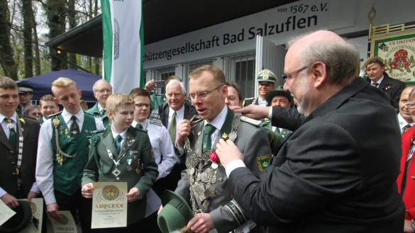 Neuer König: Matthias Drewes nimmt von Schützenkreis Lippe-Chef Dr. Stephan Breuning (verdeckt) und Peter Iwanowicz (rechts) vom Landesverband Lippe die Insignien entgegen. - © Daniel Hobein