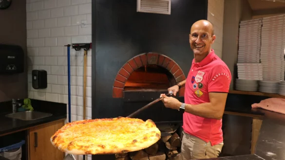 Stavros Siskas mit einer frisch gebackenen Pizza aus dem Steinofen im Hintergrund. - © Alexandra Schaller
