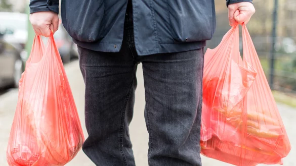 Ein Mann tr&auml;gt seine Eink&auml;ufe in Plastikt&uuml;ten nach Hause. - &copy; dpa