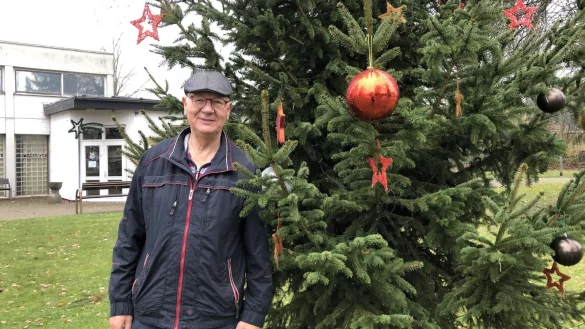 Hans Carell steht am geschm&uuml;ckten Weihnachtsbaum in der Ortsmitte von W&uuml;lfer-Bexten. Auch diesen Weihnachtsgru&szlig; w&uuml;rde es ohne den B&uuml;rgerverein nicht geben. - &copy; Thomas Reineke
