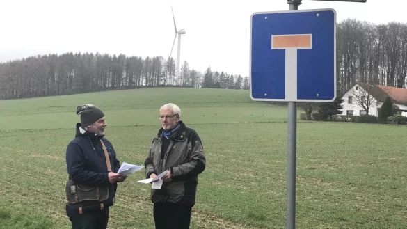 Eric Hagedorn (links) und Friedhelm Jasper stehen am Ende der Siedlung Lohholz &ndash; im Hintergrund dreht sich bereits ein W&uuml;stener Windrad. Das neue w&auml;re mehr als doppelt so hoch. - &copy; Till Brand
