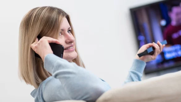 Gleichzeitig TV schauen und telefonieren &uuml;ber einen Vertrag - &copy; Foto: Christin Klose/dpa-tmn