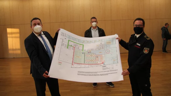Landrat Dr. Axel Lehmann (links) und Sascha Medina vom Bev&ouml;lkerungsschutz des Kreises Lippe (rechts) zeigen den Plan f&uuml;r das Impfzentrum im Kongressbereich der Phoenix Contact Arena. Dahinter ist Dr. Christian K&ouml;rner, Leiter der Bezirksstelle Detmold der Kassen&auml;rztlichen Vereinigung Westfalen-Lippe zu sehen. - &copy; Jana Beckmann