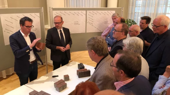 Dieser Stein soll es sein: Landschaftsarchitekt Nils Kortemeier (links) beschreibt im Kurhaus die Eigenschaften des roten Klinkers, f&uuml;r den sich die Politik im Anschluss entscheiden wird. Neben Kortemeier steht der Technische Beigeordnete der Stadt, Bernd Zimmermann. - &copy; Thomas Reineke